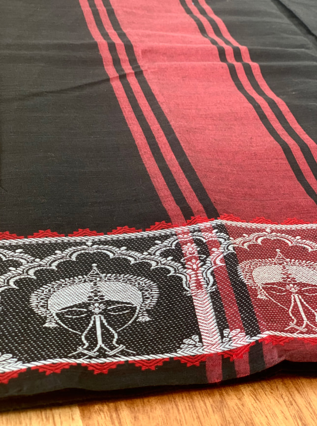 A close up of the ByGungur Anjali Saree showing the embroidered borders in red and white thread. The Gungur dancer with hands in Anjali mudra is edged with a temple motif, the white border is highlighted with red stitching in gemometric patterns.