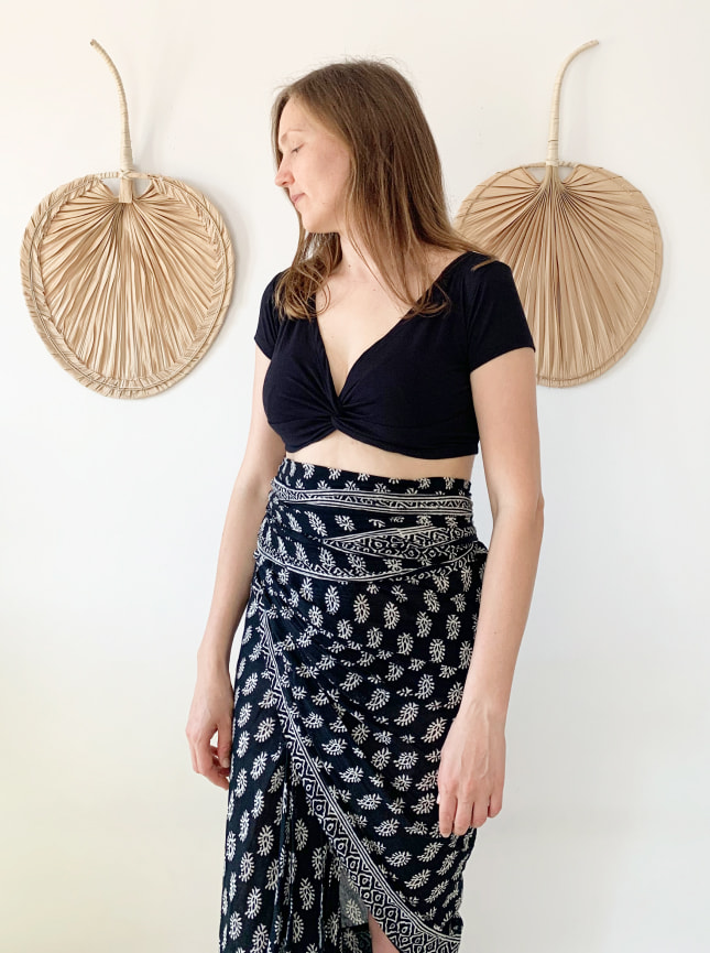 The ByGungur Pearl Crop in black is a reversable crop top. Here the model wears it as a V neck crop top with the cut away at the front. Finishing just under the bust this is a sexy and revealing look. The model is wearing the Pearl Crop top with the ByGungur block print wrap skirt