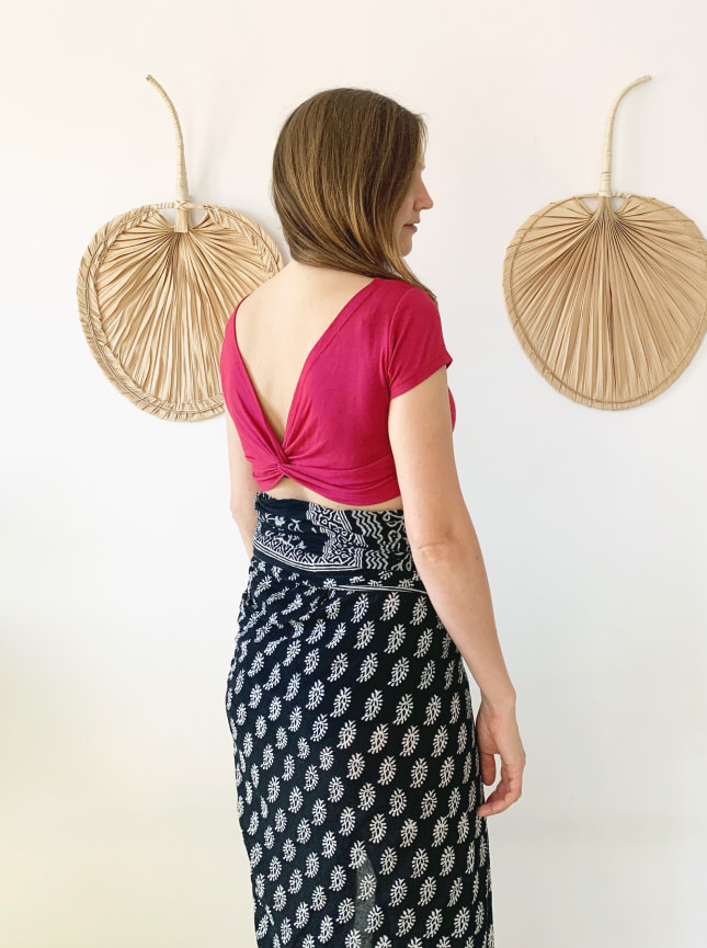 The ByGungur Pearl Crop is a multiuse crop top that can be worn with the deep cut away V at the fron or at the back. Here the model is wearing the Pearl Crop top in Orquidea red with the cutaway V at the back. She is wearing it with the Block Print black and white Wrap worn as a skirt.